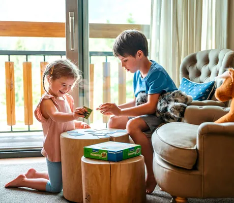 Zwei Kinder spielen auf einem kleinen Tisch in einem Zimmer im Familienhotel Sonnenalp Resort