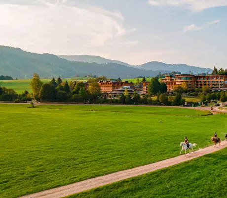 Eine Reitgruppe reitet auf einem Weg in der Nähe vom Familienhotel Sonnenalp Resort
