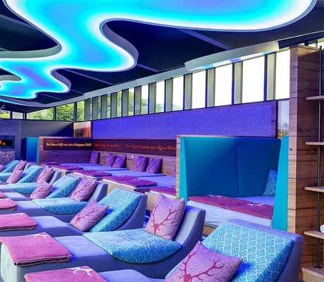 Ruheraum mit blau-lila Kissen und wellenförmiger Lampe_Heselbacher Hof