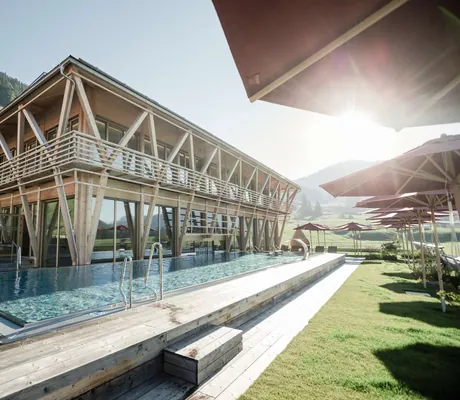 Außenansicht des Hundehotel HUBERTUS Mountain Refugio mit der aufsteigenden Sonne im Hintergrund