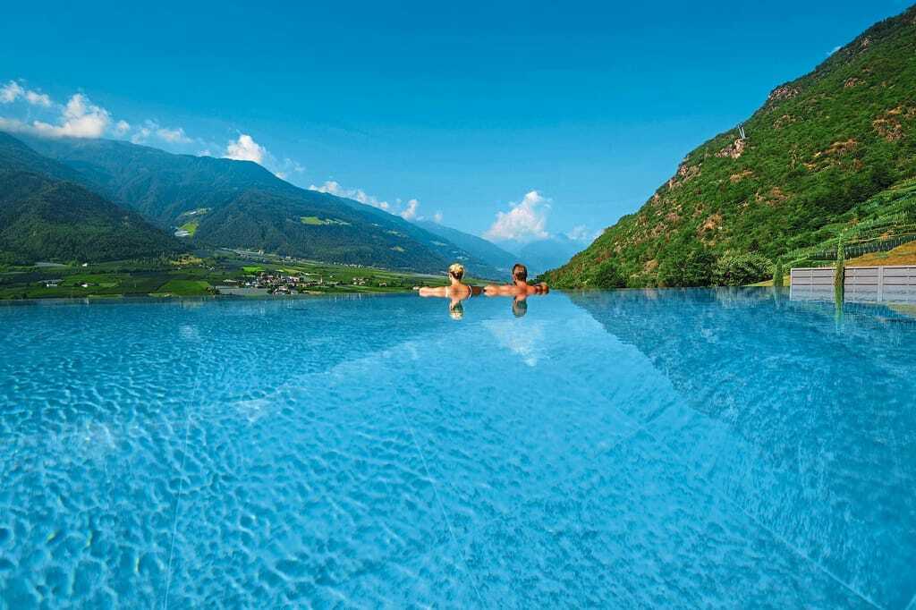 Pärchen blickt vom Infinity Pool aus auf die Berglandschaft im Preidlhof