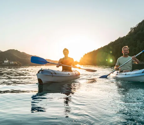 Eine Frau und ein Mann beim Kajakfahren am Fuschl See in der Nähe des Sporthotel Ebner’s Waldhof am See Alpines Spa und Golf Resort