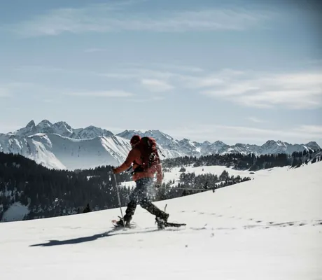 Mann beim Schneeschuhwandern vor wunderschöner Bergkulisse