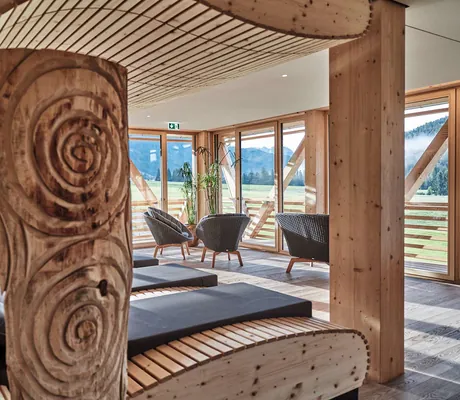 Ruheraum des Sporthotel HUBERTUS Mountain Refugio mit mehreren Liegen und Blick nach außen durch bodentiefe Fenster