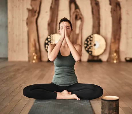 Frau beim Yoga im Yogaraum des Sporthotel HUBERTUS Mountain Refugio
