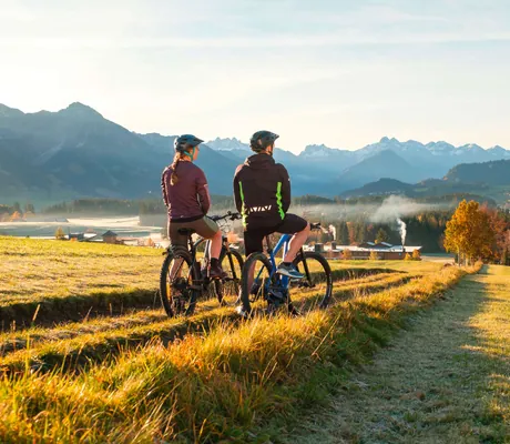 Zwei Fahrradfahrer pausieren auf einer Wiese beim Sporthotel Sonnenalp Resort