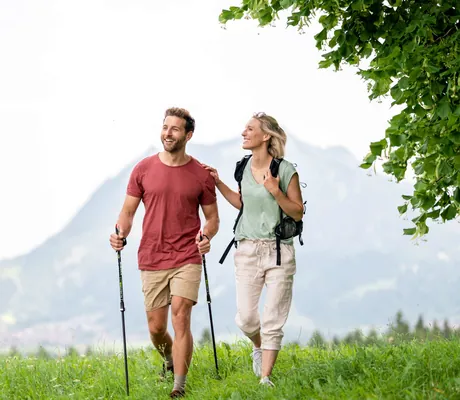 Eine Frau und ein Mann beim Wandern durch die Wiesen beim Sporthotel Sonnenalp Resort