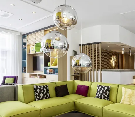 Open Lobby mit Lounge-Sofalandschaft, Kugellampen im Sixties-Style und Rezeption