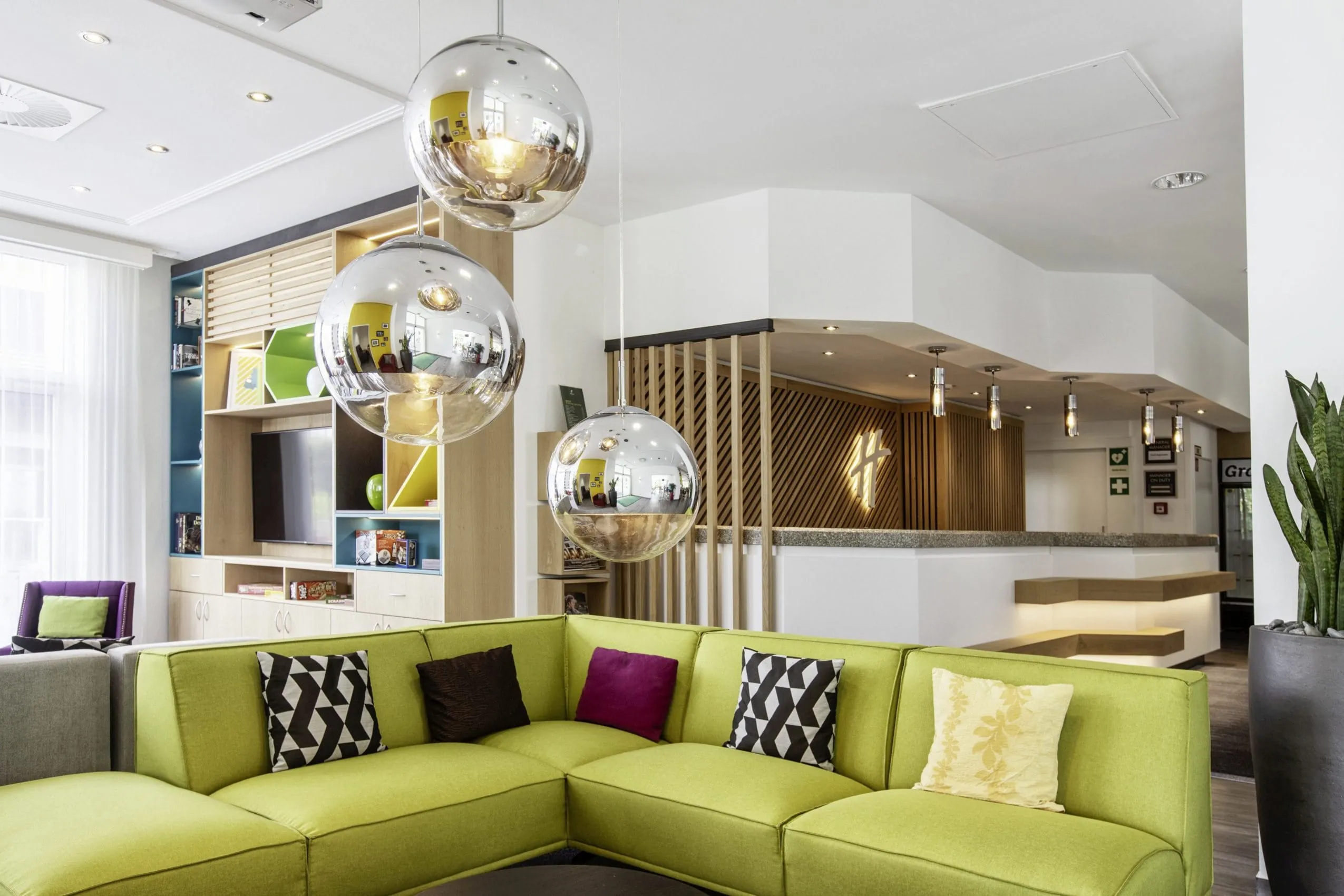 Open Lobby mit Lounge-Sofalandschaft, Kugellampen im Sixties-Style und Rezeption