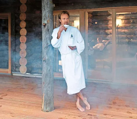 Mann steht an eine Pfahl gelent vor der Sauna_HotelBornmühle_GroßNemerow