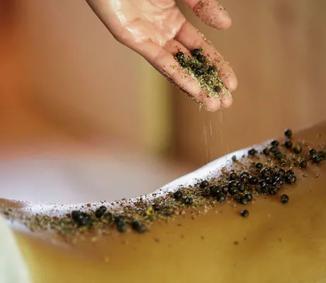 Eine Frau bekommt eine Salzpeeling-Behandlung im Wellnesshotel HUBERTUS Mountain Refugio Allgäu