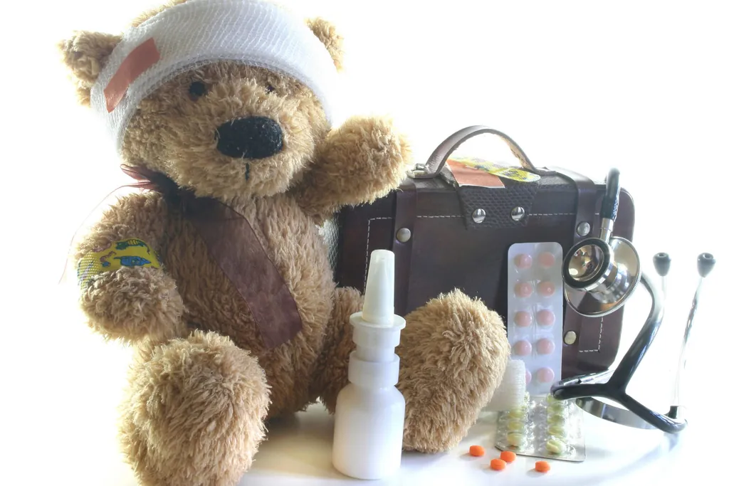 Teddybär mit Verband, daneben Reiseapotheke