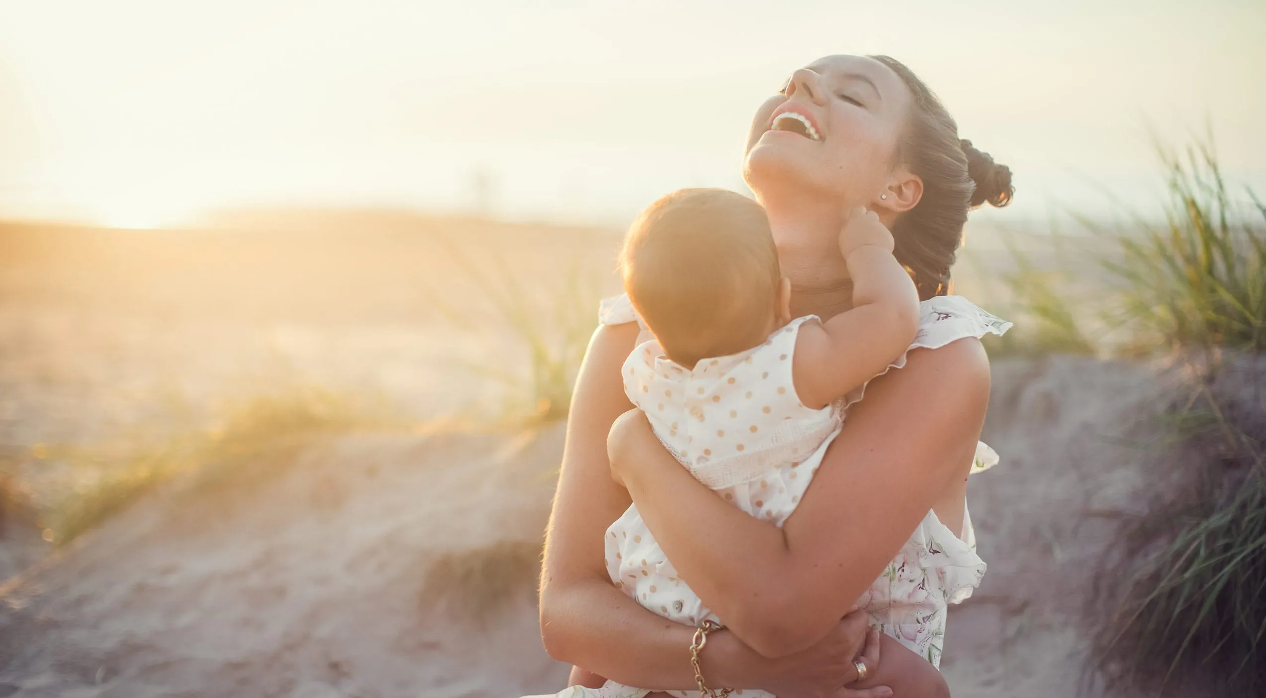 Junge Frau am Strand mit Baby auf dem Arm