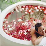 Symbolbild Wellnessurlaub: Frau liegt in einer Badewanne mit Blumen