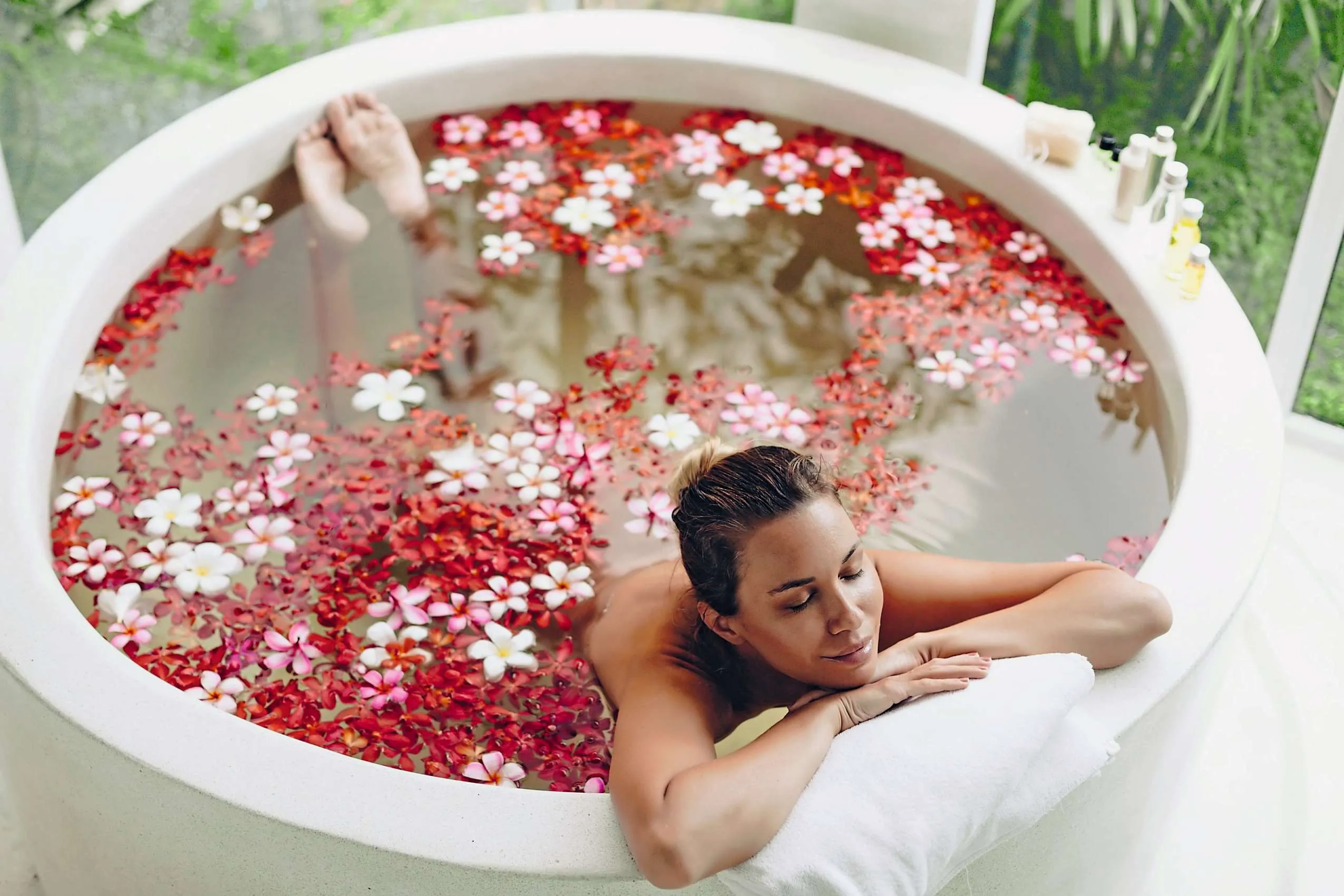 Symbolbild Wellnessurlaub: Frau liegt in einer Badewanne mit Blumen