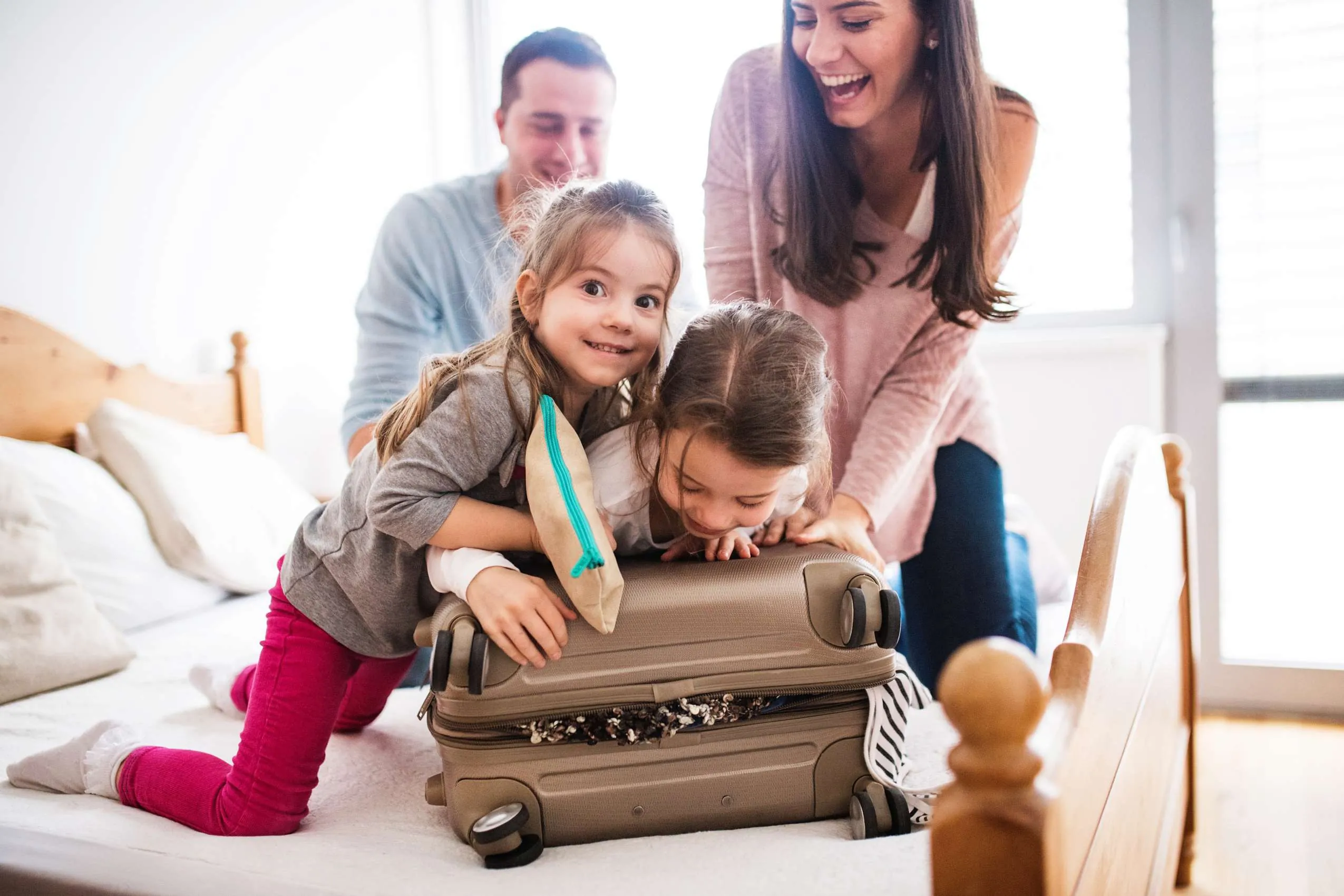 Mama, Papa und zwei Kinder packen fröhlich den Urlaubskoffer für den Familienurlaub