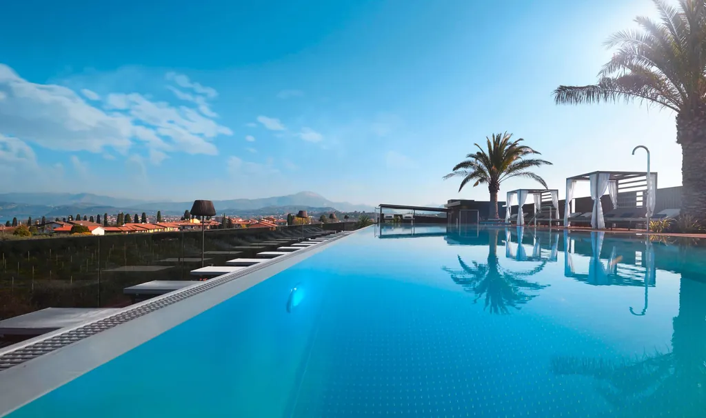 Vom Rooftop-Pool Quellenhof Lazise sieht man den Gardasee und die Berge der Gegend.