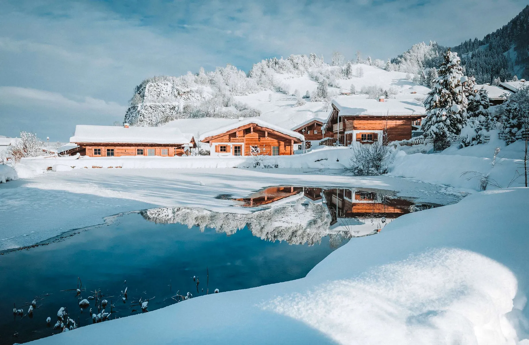 zugefrorener Teich vor eigenschneiten Chalets