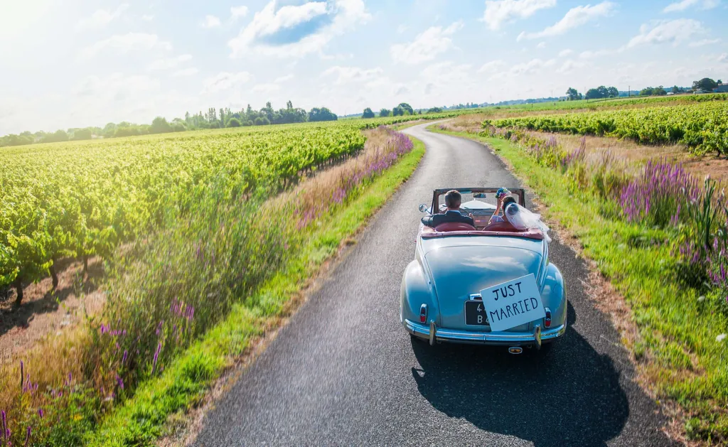 Flitterwochen in Deutschland: Ein frisch vermähltes Paar fährt in einem Oldtimer.