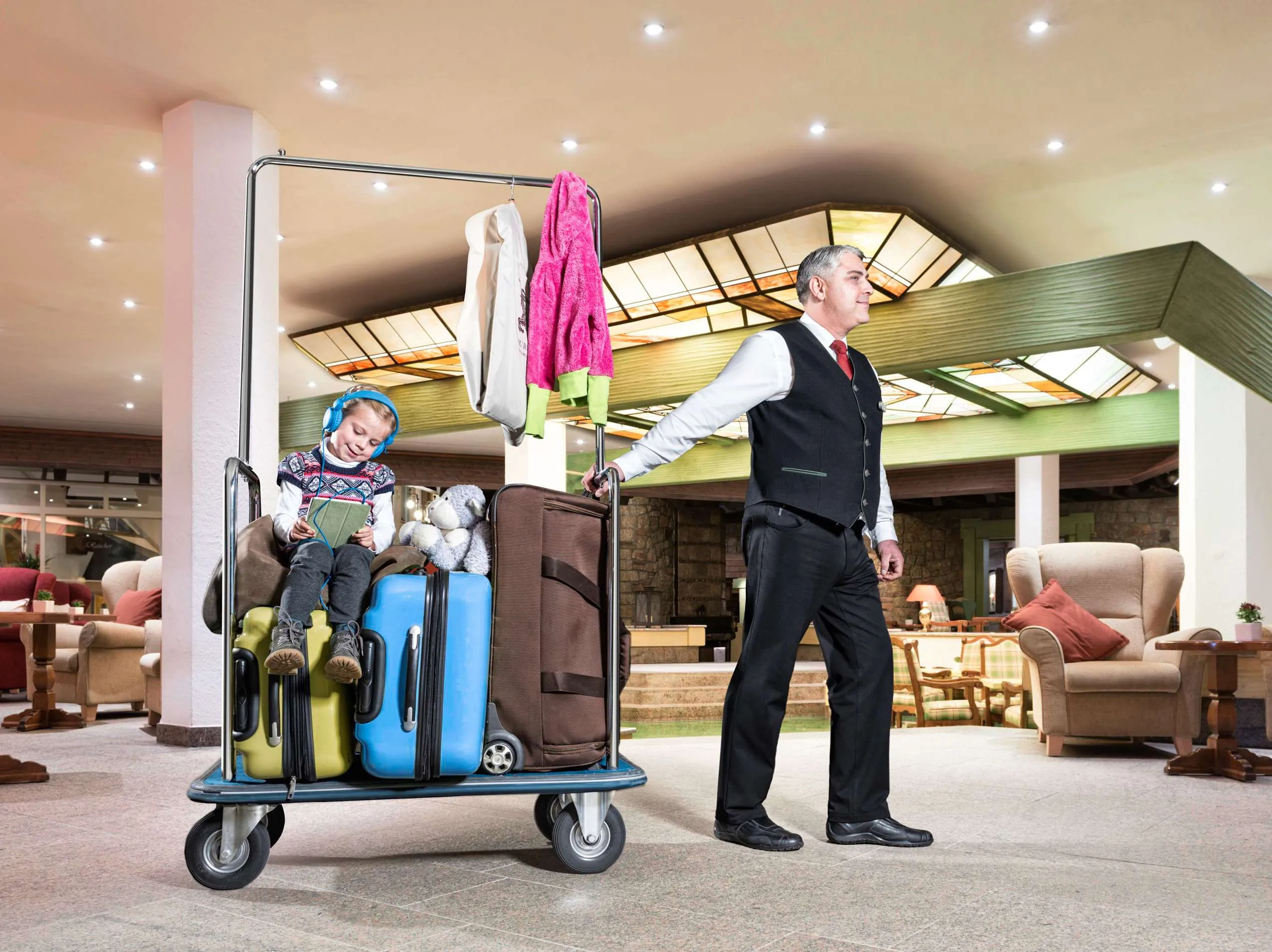 Page zieht M&auml;dchen auf Kofferwagen durch die Lobby