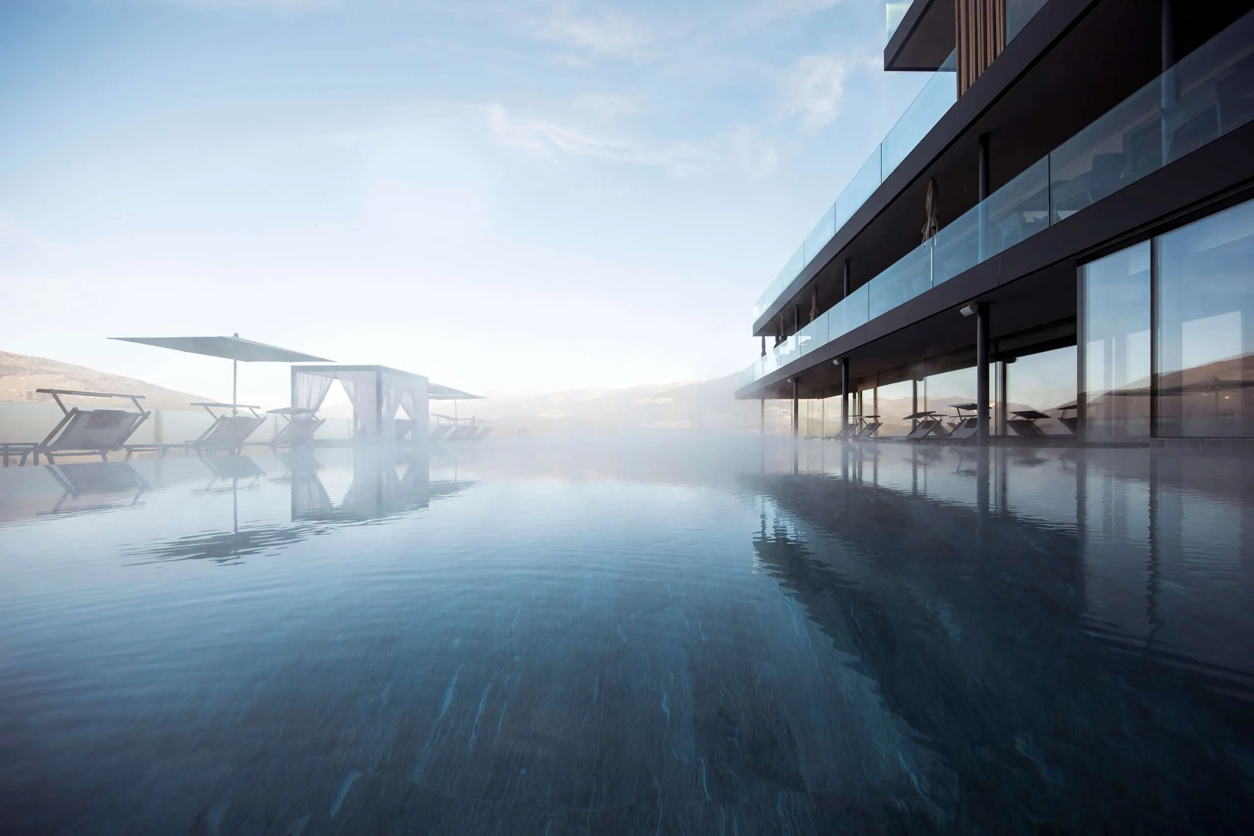 Infinitypool mit weißen Schirmen am Hotelgebäude