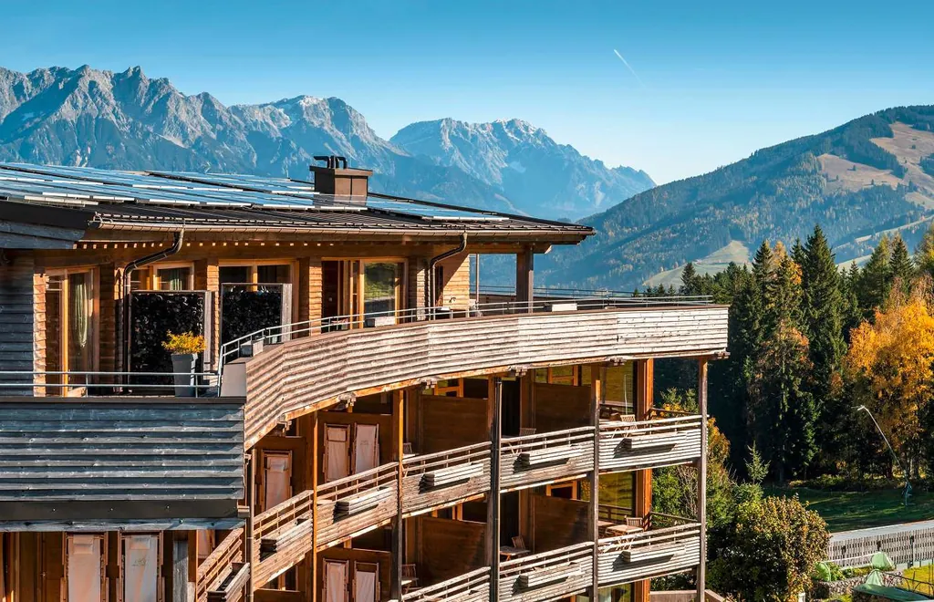 Außenansicht auf die Zimmerbalkone des Holzhotels Forsthofalm mit Bergen im Hintergrund
