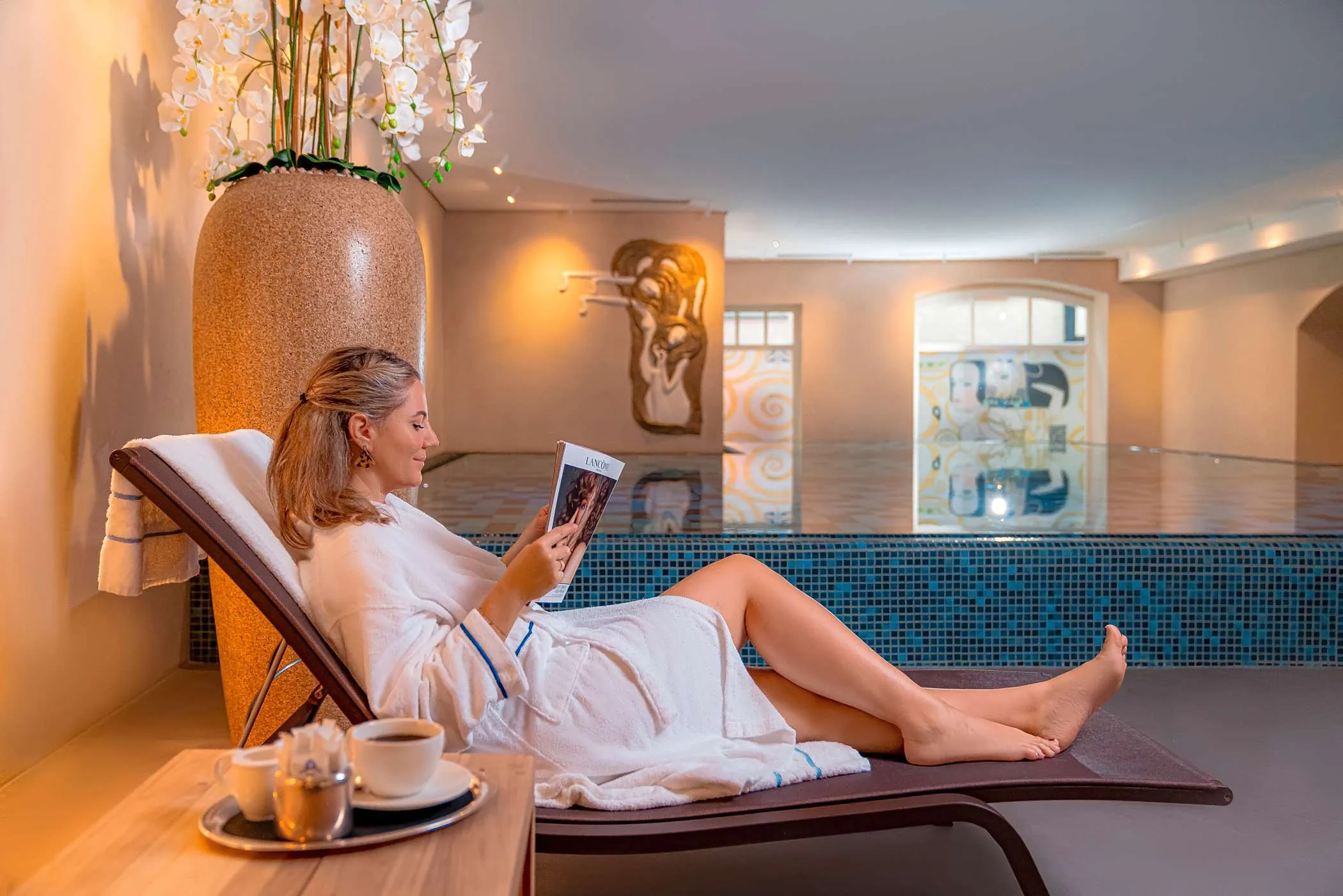 Frau Sitz auf einer Liege vor dem Pool und genie&szlig;t ihren Wellnessurlaub im Romantik Jugenstilhotel BELLEVUE.