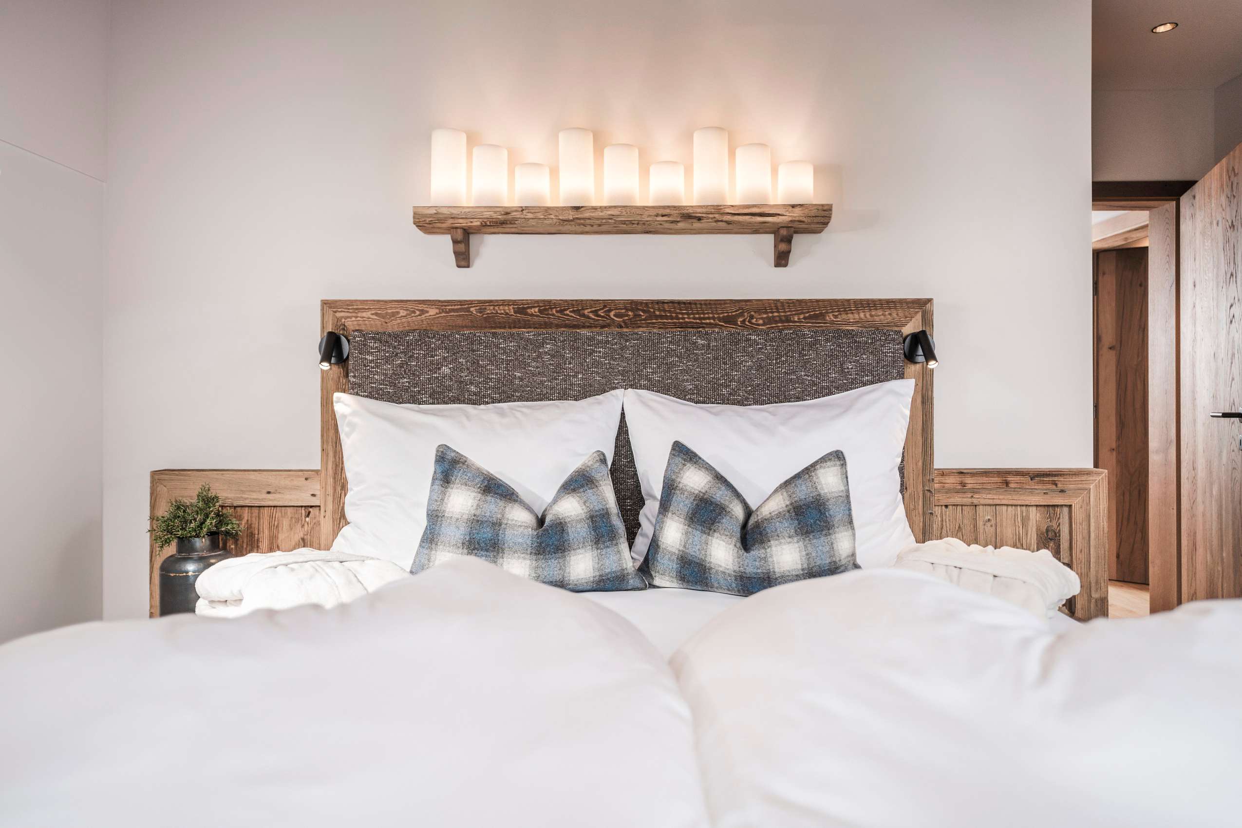 Doppelbett mit blau-weiß karierten Kissen_FarmResortGeislerhof