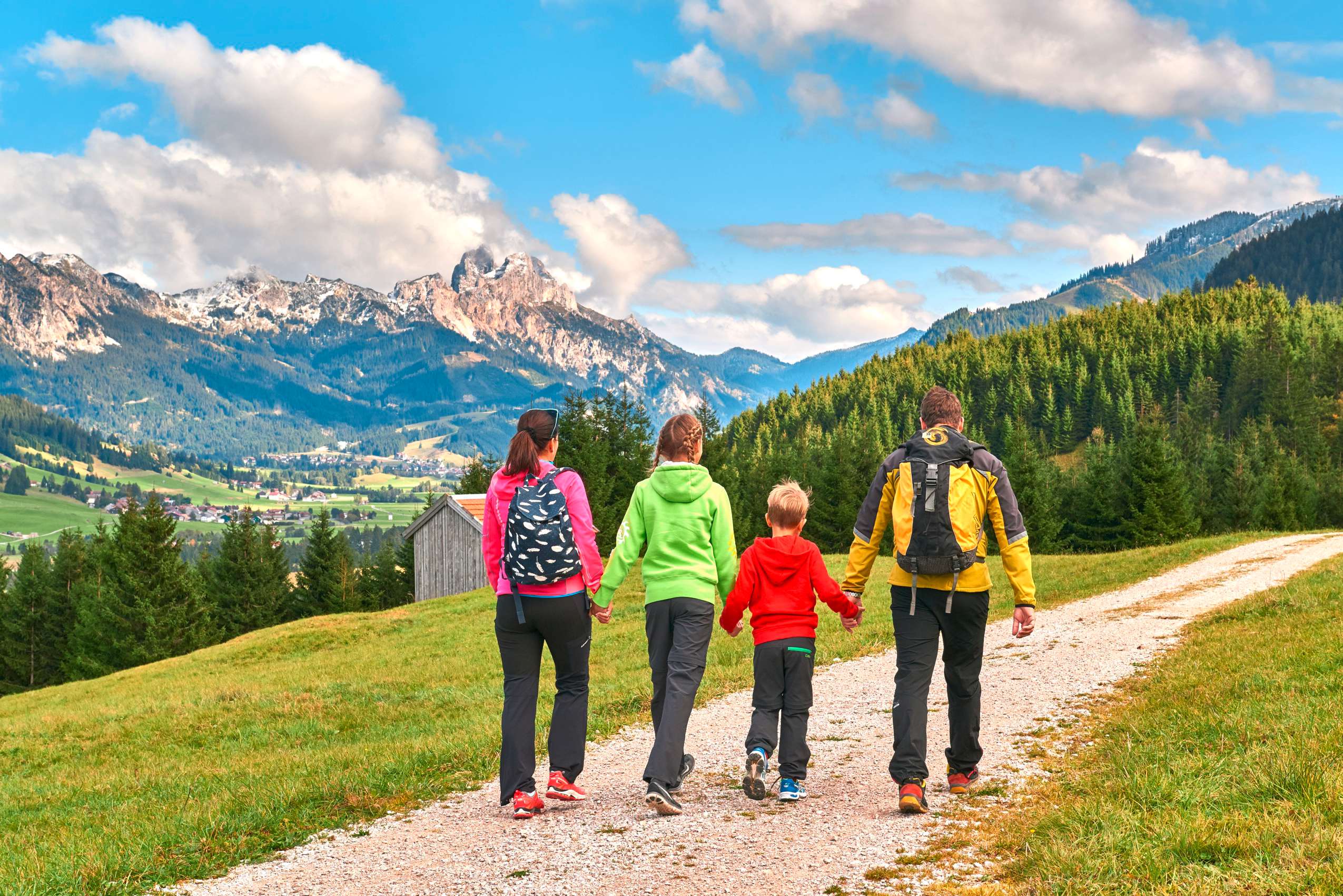 Blick auf Familie die Hand in Hand durch die Berglanschaft wandert_ChavidaChalets