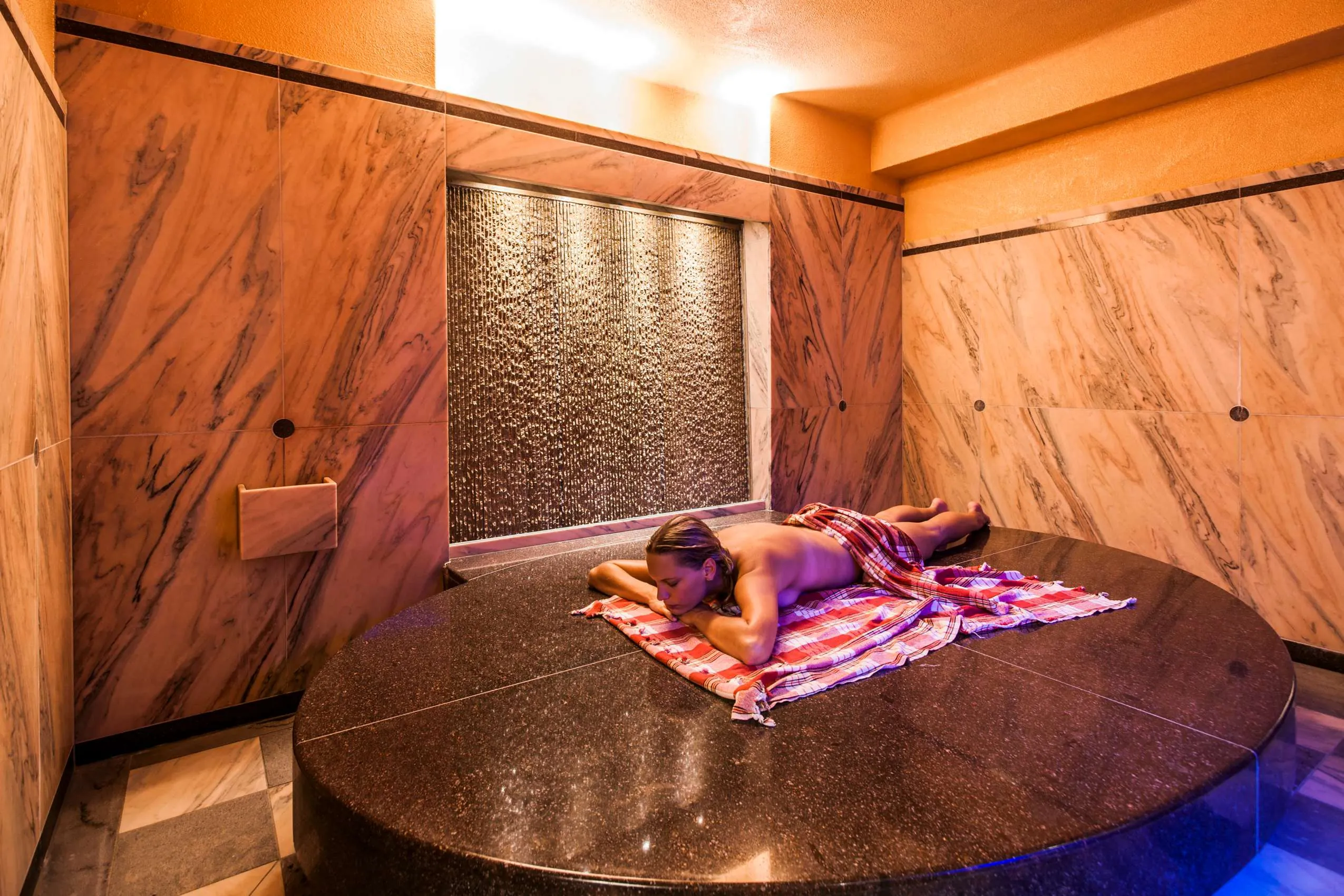 Frau liegt auf erh&ouml;htem Podest und erh&auml;lt Hamam-Behandlung