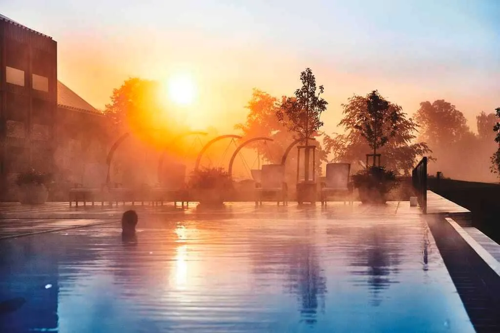 Frau schwimmt im Abendrot im Außenpool des Öschberghofs