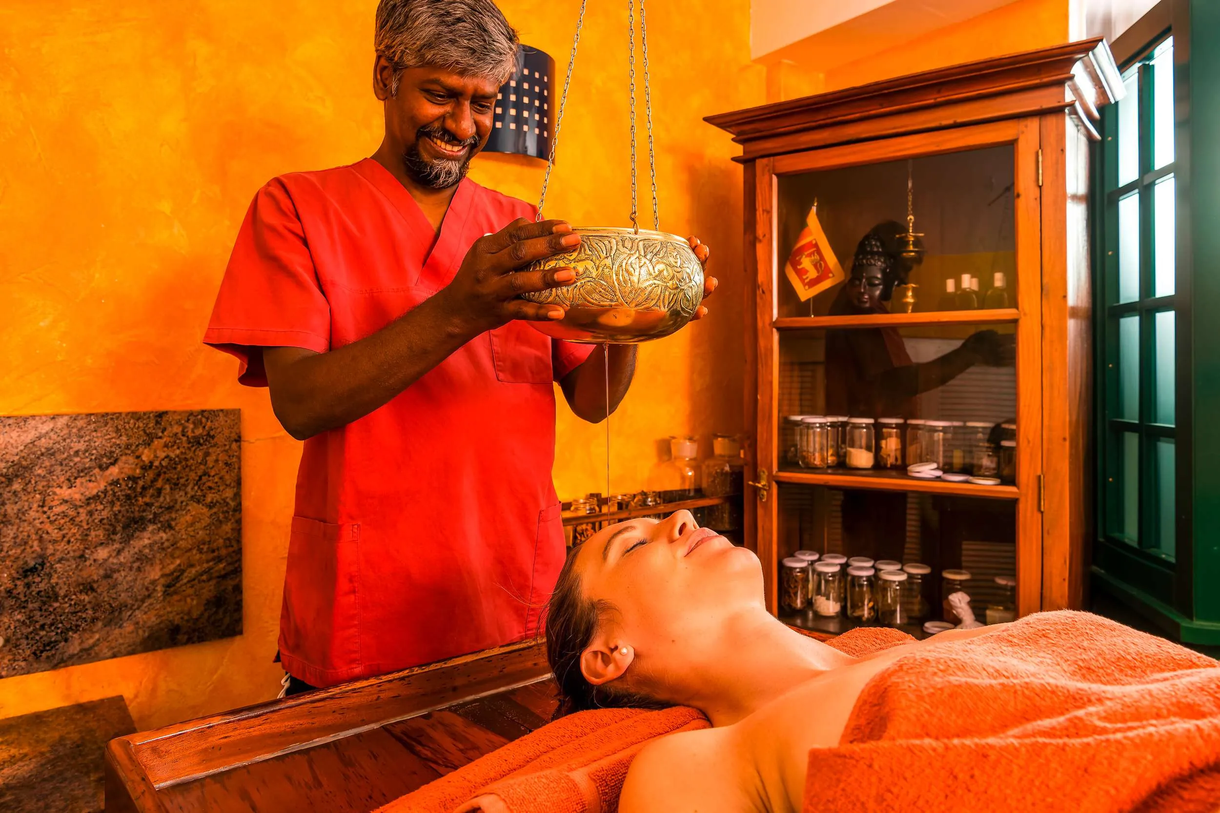 Junger Frau wird w&auml;hrend einer Ayurveda-Anwendung im Hotel Vier Jahreszeiten am Schluchsee &Ouml;l auf die Stirn getr&ouml;pfelt