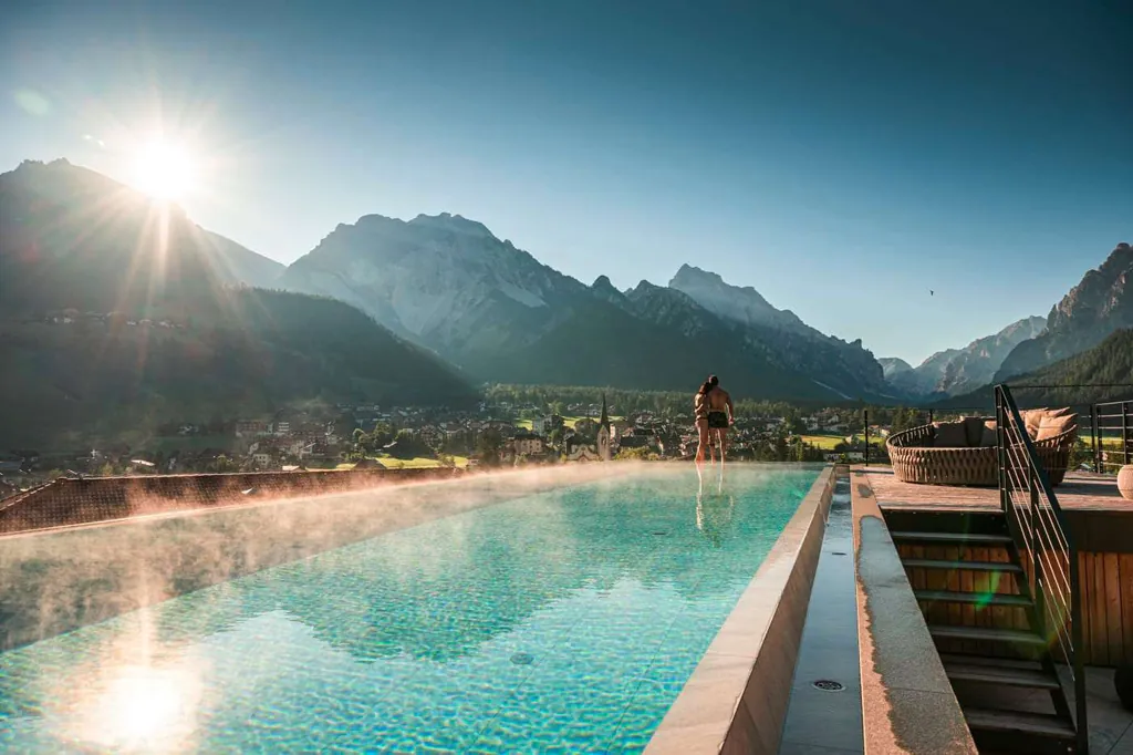Paar steht am Ende des Infinity-Pools im Excelsior Dolomites Life Resort