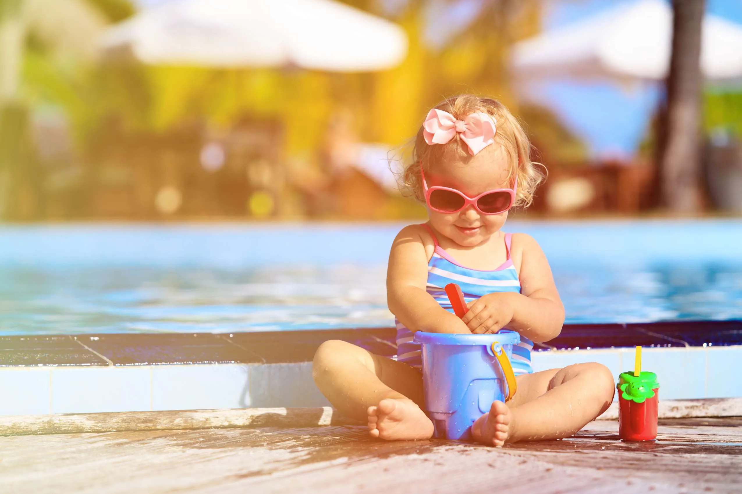 Kleines Mädchen spielt mit Eimer vor Pool im Babyhotel