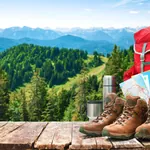 Wanderrucksack, Wanderschuhe und Wanderkarte vor Bergpanorama