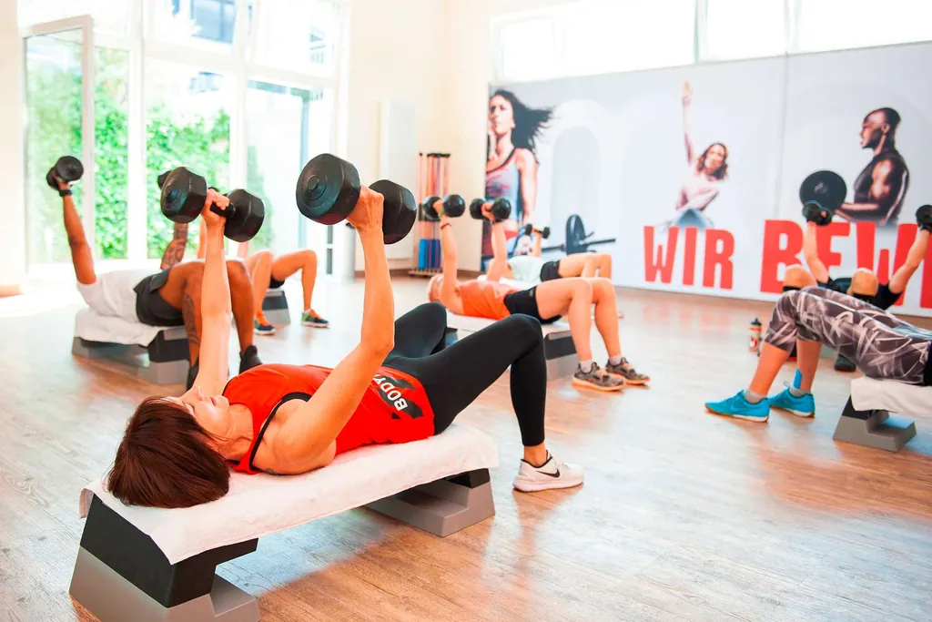 Gruppe im Fitnessstudio macht Body-Toning-Übungen mit Kurzhanteln