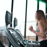 Junge Frau beim Cardio-Training auf dem Laufband im Fitnessstudio