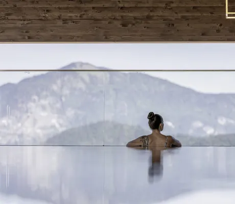 Eine Frau genießt den Blick auf die Berge vom Pool der Hygna Chalets