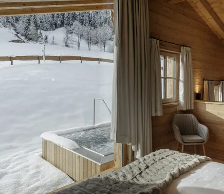 Blick aus einem Chalet der Hygna Chalets auf den Garten mit privatem Whirpool im Winter in Österreich
