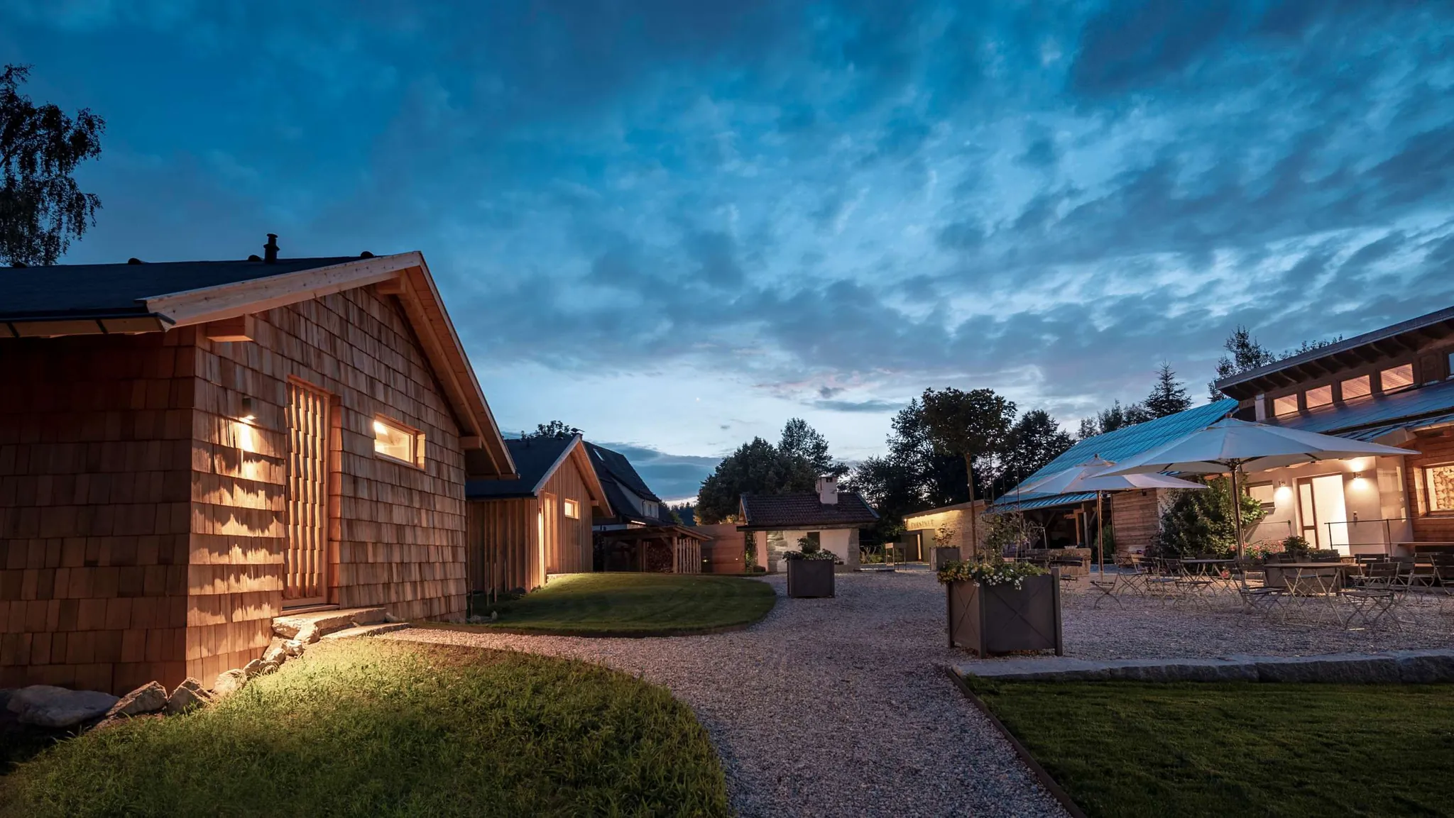 Innehof mit weißen Schirmen umrundet von Holz-Chalets