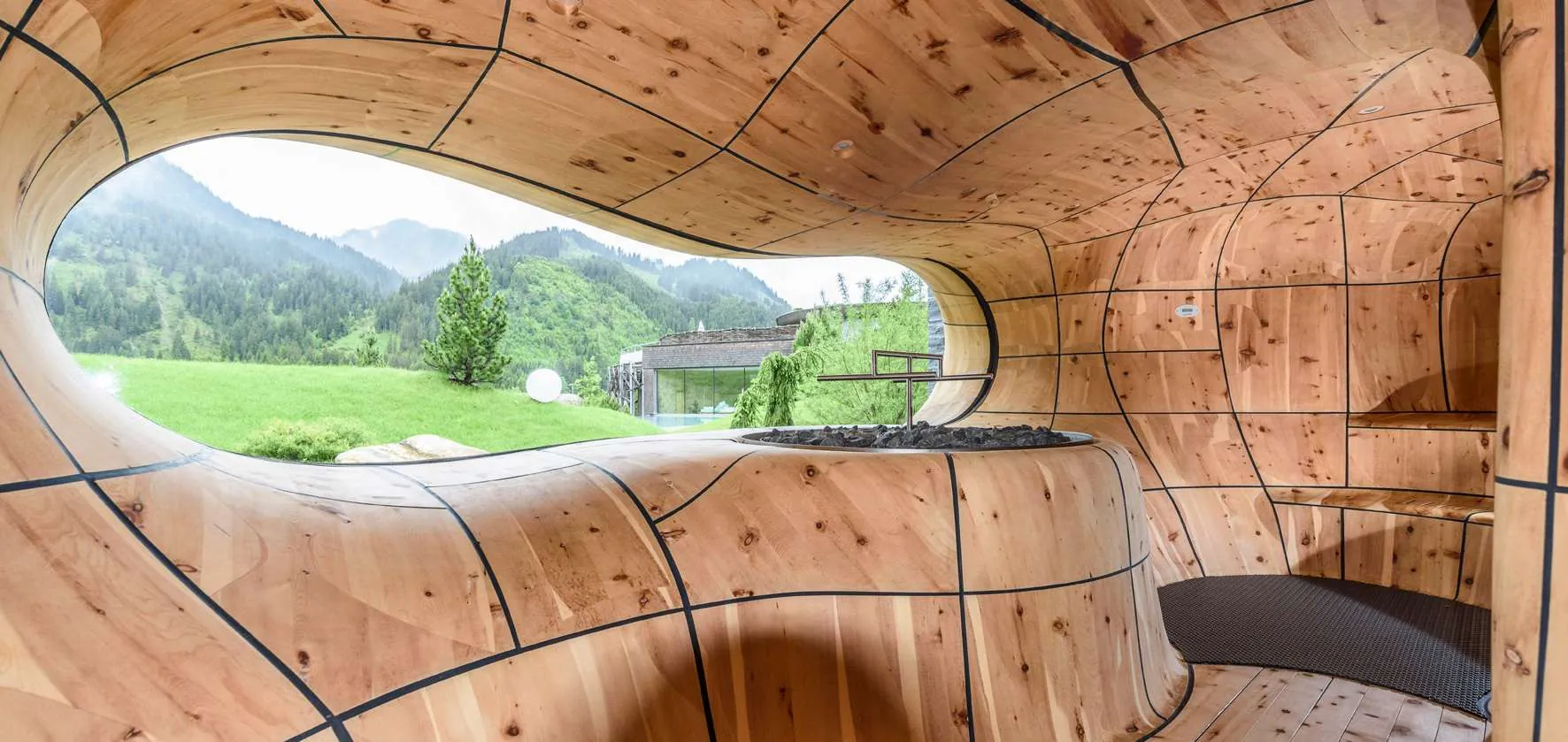 Ovales Fenster in handgeschnitzter Bergsauna im Wellnesshotel Jungbrunn in Tirol