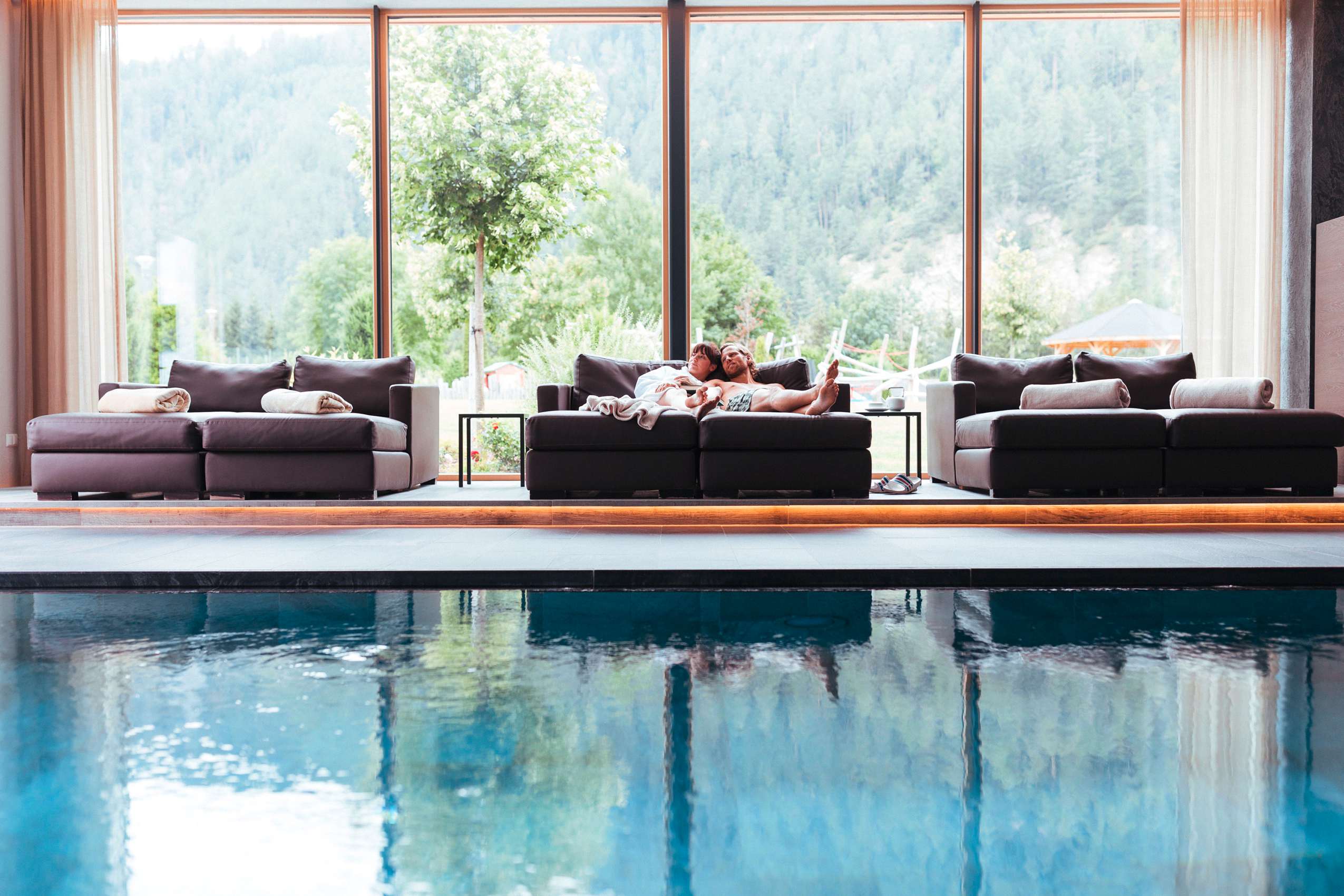 Paar auf Ruhesofa am Indoorpool