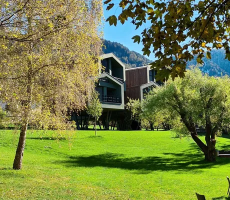 Der riesige Hotelpark mit alten Bäumen vor den Chalets im Hintergrund
