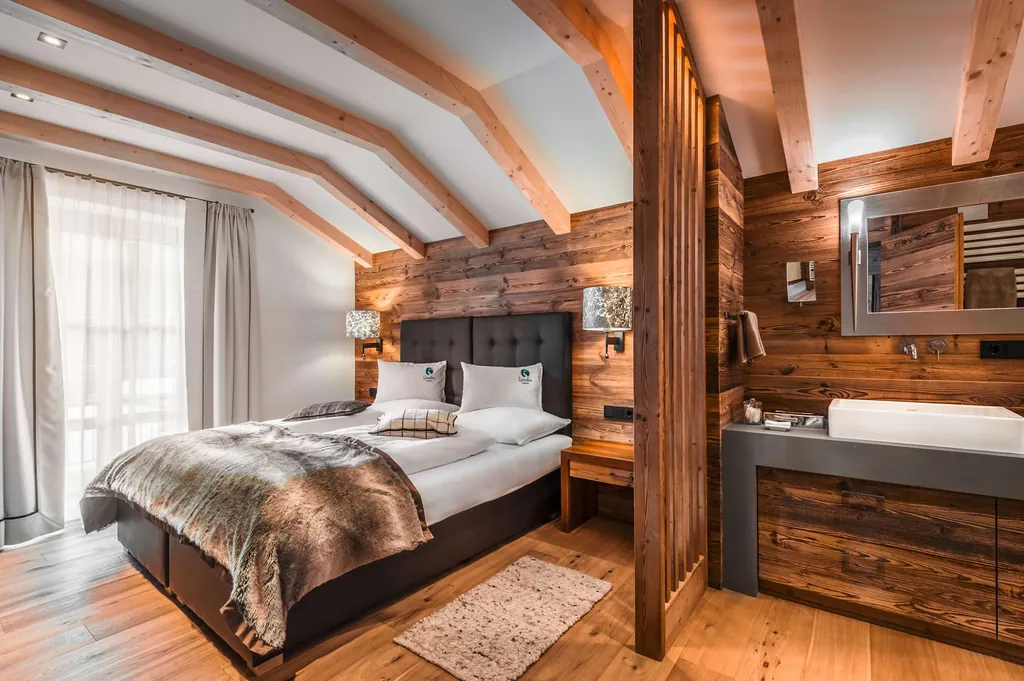Doppelbett unter Holzbalkendecke und Blick ins Bad