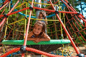 Mädchen schaukelt auf grüner Netzschaukel und lacht