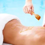 Honig wird für eine Honigmassage auf dem Rücken einer Frau verteilt