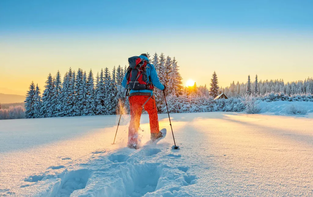 Mann wandert in Schneeschuhen über ein schneebdecktes Feld