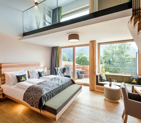 Loft Zimmer zweistöckig mit Bett, Sofa, Tisch, Stuhl und großen Fenstern