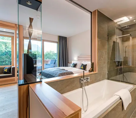 Panoramaausblick aus dem Badezimmer mit Badewanne durch Schlafzimmer mit Bett