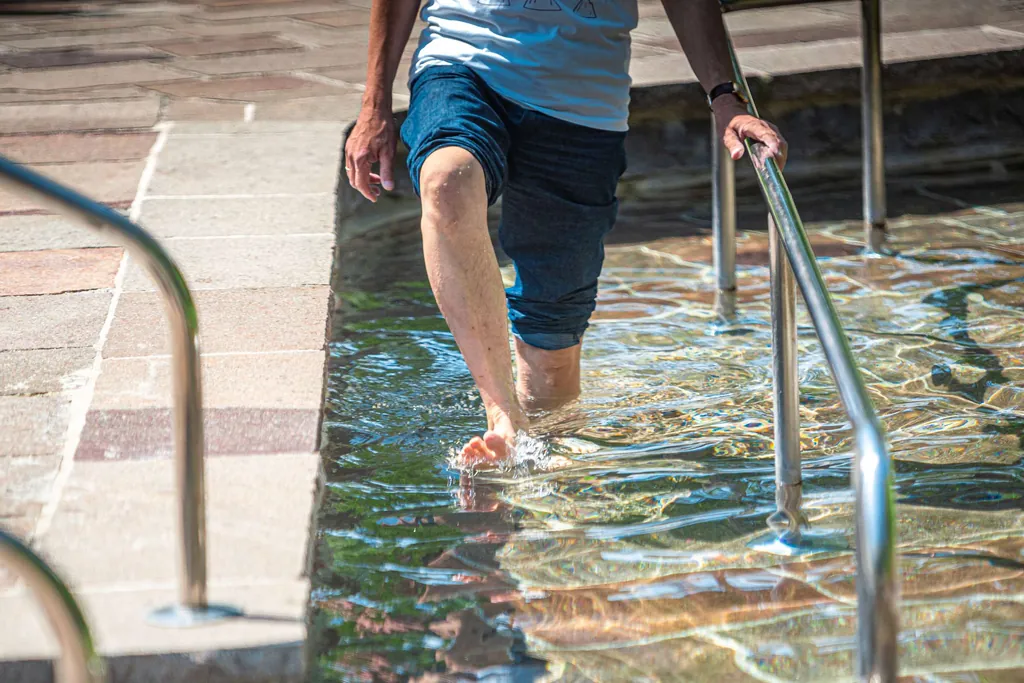 Mann läuft mit nackten Füßen durch ein Kneipp-Fußbecken
